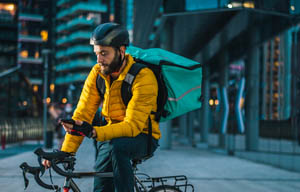 Bicycle courier in the city, checking his smartphone.